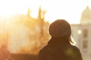 woman standing with her back turned facing sunrise wearing beanie and embracing life after rehab